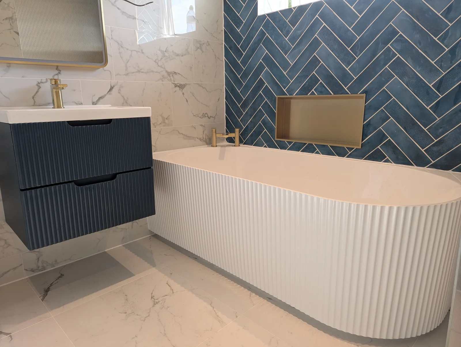 Luxury bathroom in Dartford with blue herringbone tiles and freestanding bath