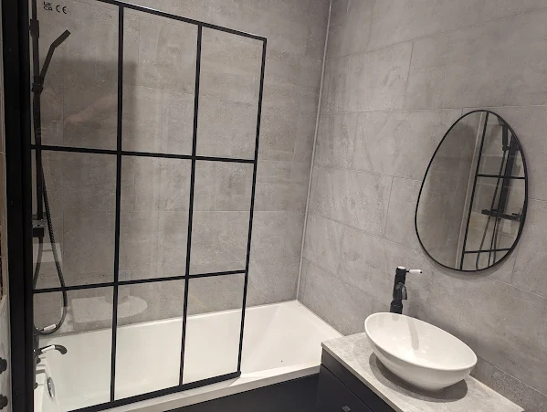 Modern grey bathroom with crittall-style shower screen and round mirror