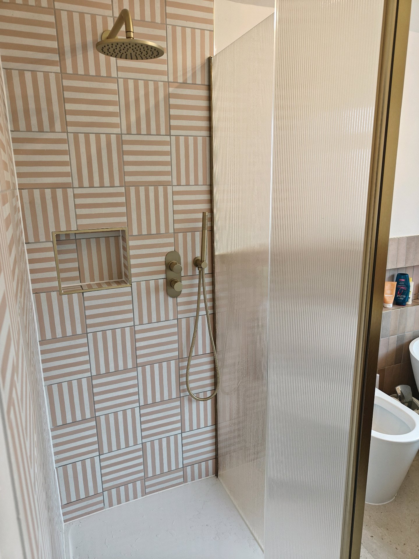After: Designer shower with striped tiles and brass fittings