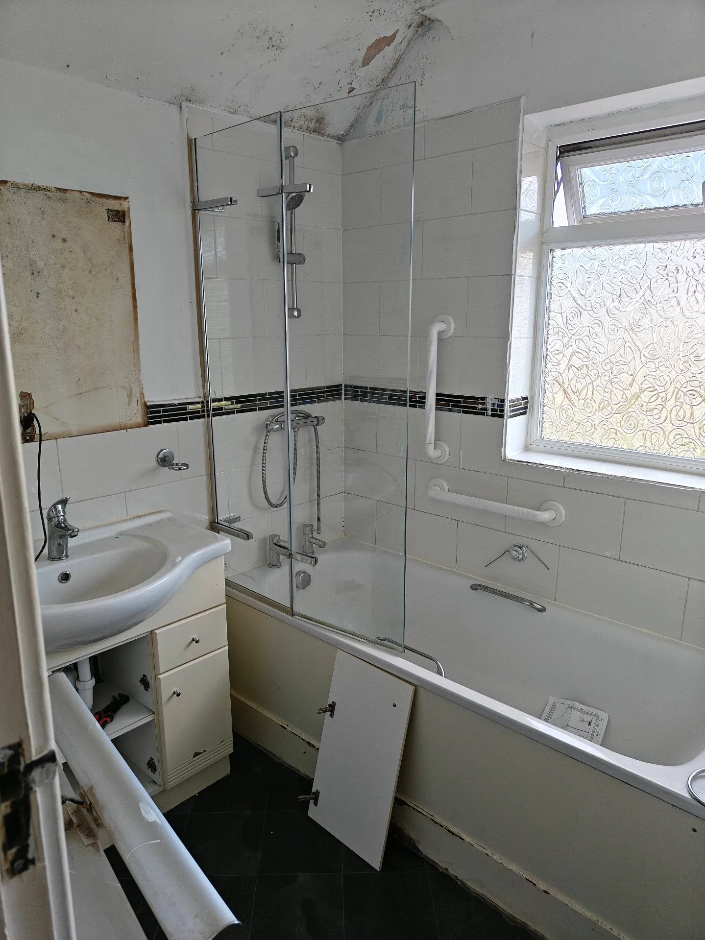 Before: dated bathroom with mould on the ceiling, old shower bath and worn vanity unit