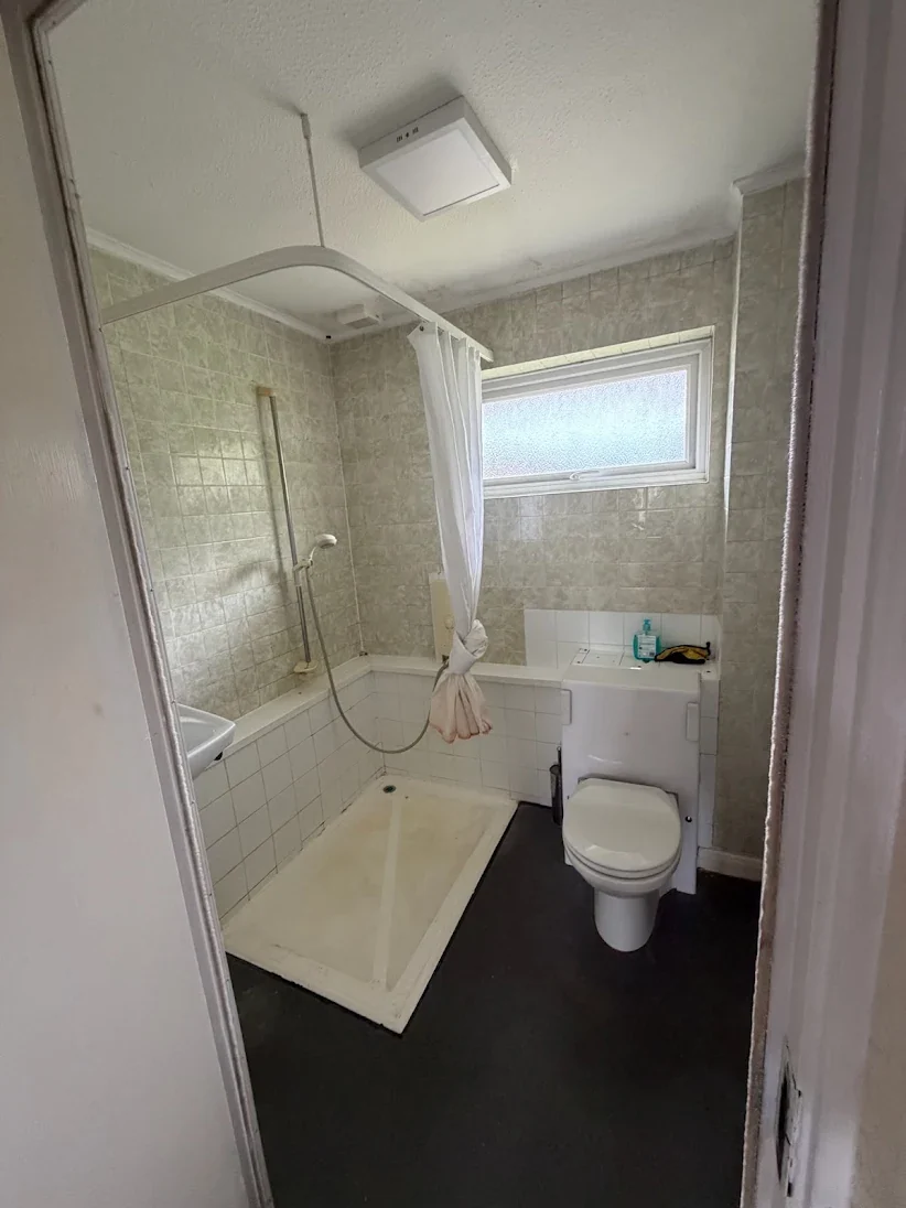 Before: a dated bathroom in Kemsing with a corner shower tray, plastic curtain rail, beige wall tiles and a boxed-in cistern